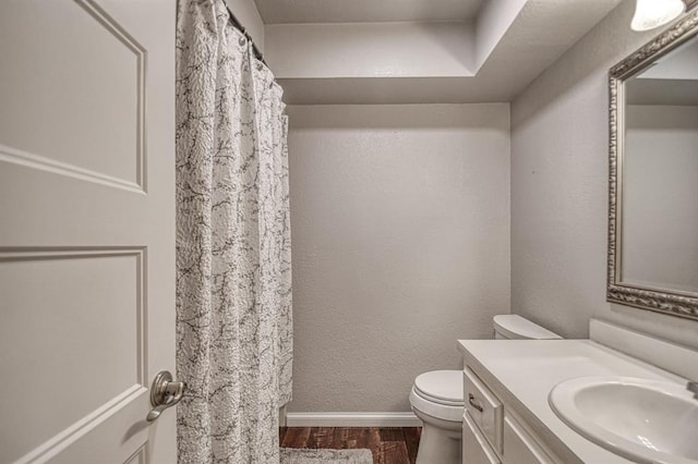 bathroom with vanity, wood finished floors, toilet, and baseboards