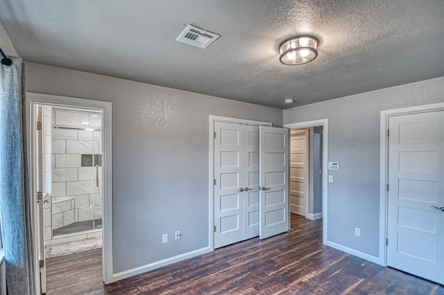 unfurnished bedroom with a closet, dark wood-style flooring, visible vents, and baseboards