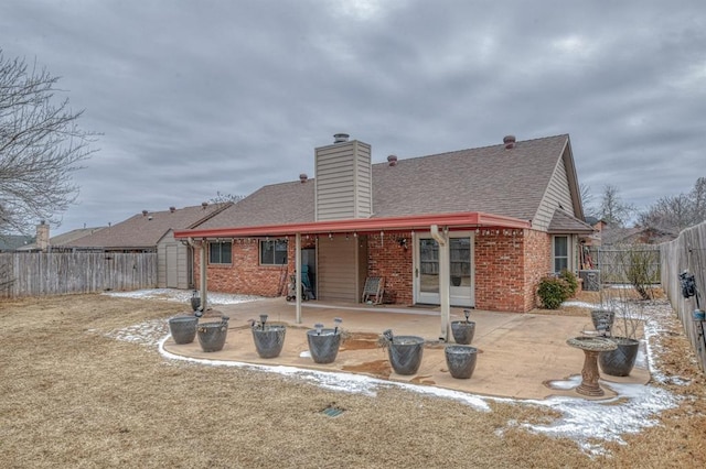 back of property with a patio area, a fenced backyard, a chimney, and brick siding