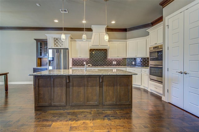 kitchen with dark hardwood / wood-style floors, a center island with sink, stainless steel appliances, and decorative light fixtures