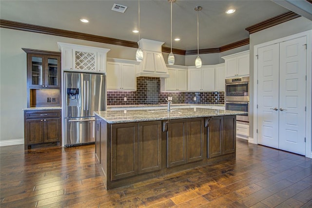 kitchen with dark hardwood / wood-style flooring, pendant lighting, a center island with sink, and appliances with stainless steel finishes