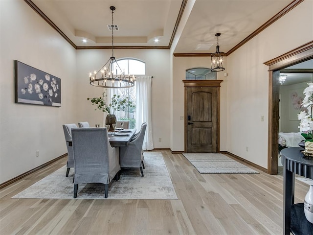 dining room featuring ornamental molding, a tray ceiling, light hardwood / wood-style floors, and a notable chandelier