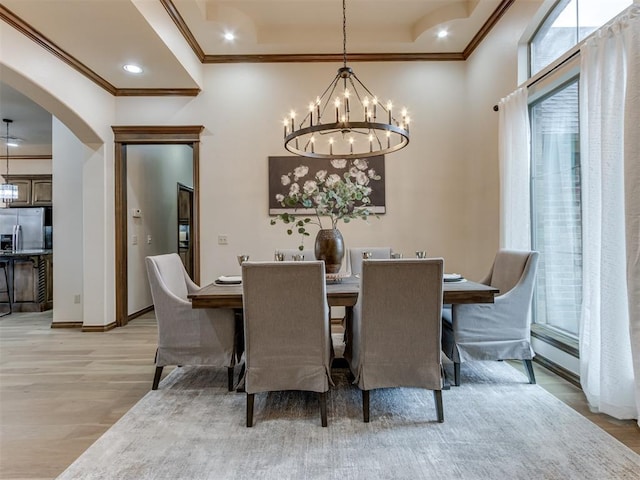 dining space with crown molding, a chandelier, and light hardwood / wood-style flooring