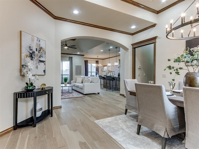 dining area featuring ceiling fan with notable chandelier, ornamental molding, and light hardwood / wood-style floors