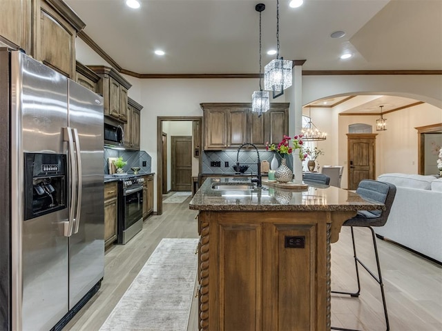 kitchen featuring a center island with sink, appliances with stainless steel finishes, sink, and pendant lighting