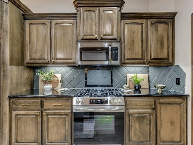 kitchen featuring stainless steel appliances, decorative backsplash, and dark stone counters