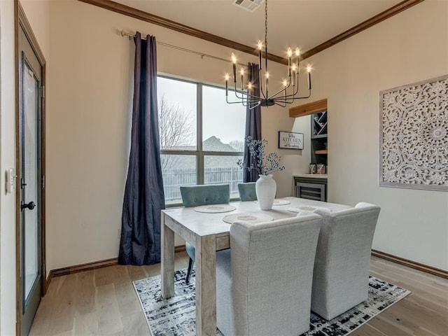 dining space with crown molding, a notable chandelier, and light hardwood / wood-style flooring