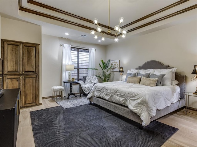 bedroom with crown molding, light hardwood / wood-style floors, and a tray ceiling