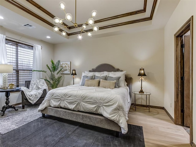 bedroom featuring an inviting chandelier, ornamental molding, a raised ceiling, and light wood-type flooring