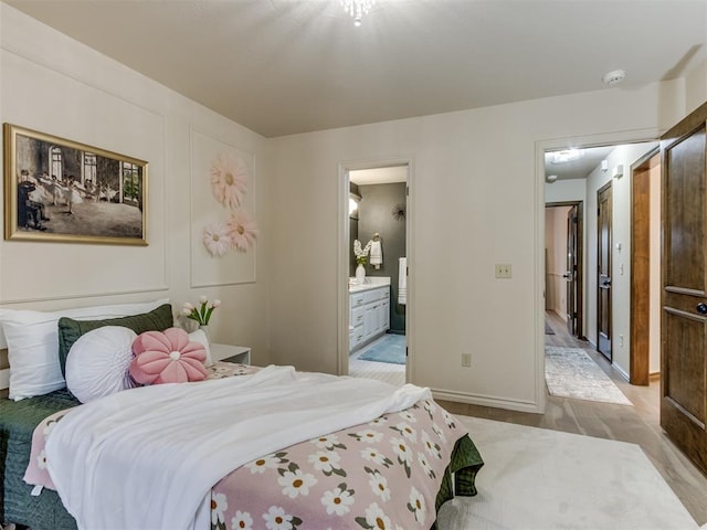 bedroom featuring ensuite bath and light wood-type flooring