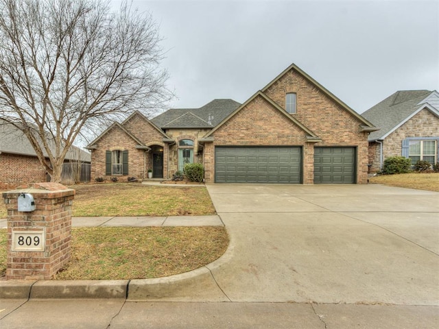 view of front facade featuring a front yard, fence, driveway, an attached garage, and brick siding