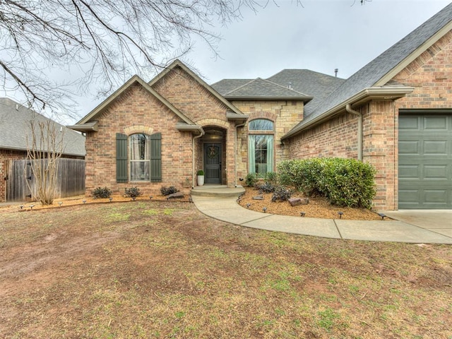 view of front of house featuring an attached garage, fence, brick siding, and a shingled roof