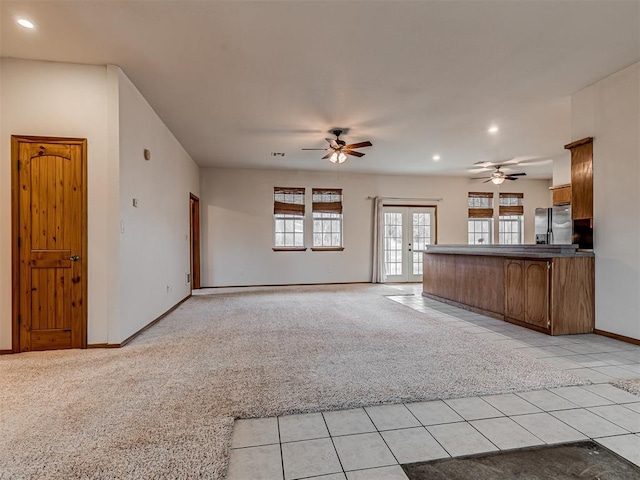 unfurnished living room with ceiling fan, light carpet, and french doors