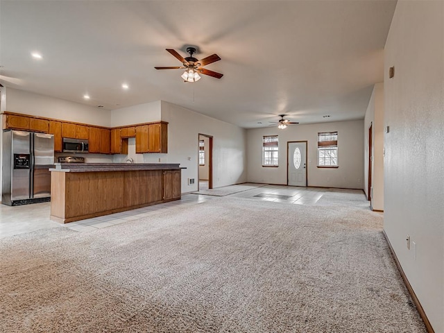 kitchen featuring light carpet, appliances with stainless steel finishes, a kitchen island, and ceiling fan