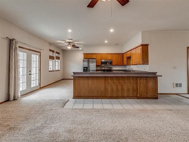 kitchen featuring french doors, sink, appliances with stainless steel finishes, light colored carpet, and kitchen peninsula