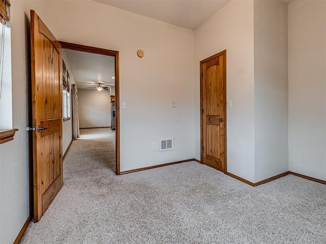 empty room featuring ceiling fan and light colored carpet