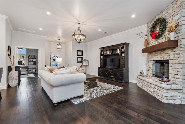 living room with an inviting chandelier, a stone fireplace, dark wood-type flooring, and crown molding