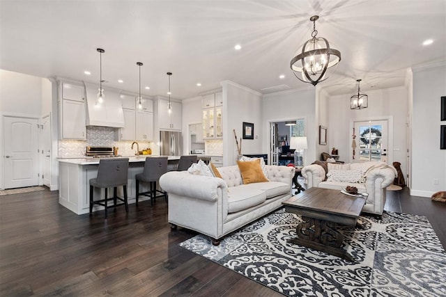 living room featuring sink, crown molding, dark hardwood / wood-style floors, and a chandelier