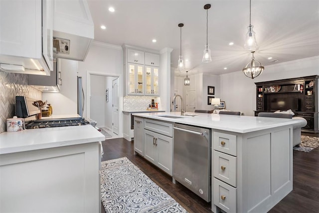 kitchen with sink, hanging light fixtures, a center island with sink, stainless steel appliances, and white cabinets