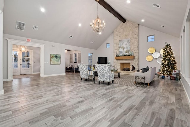 living room with beam ceiling, high vaulted ceiling, a notable chandelier, a stone fireplace, and light wood-type flooring