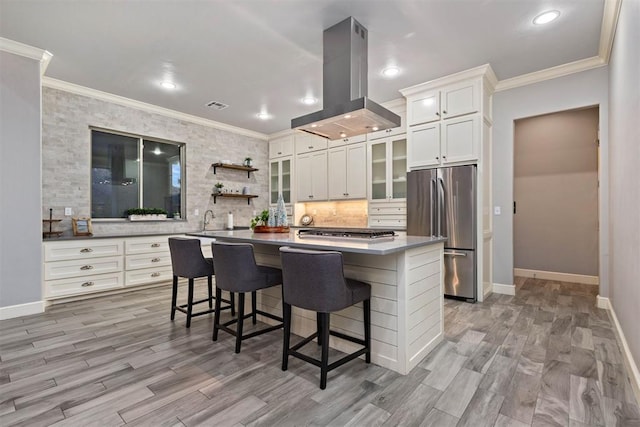 kitchen with a kitchen island, appliances with stainless steel finishes, a breakfast bar, island range hood, and white cabinets