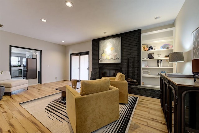 living room featuring light wood-type flooring, a brick fireplace, and plenty of natural light