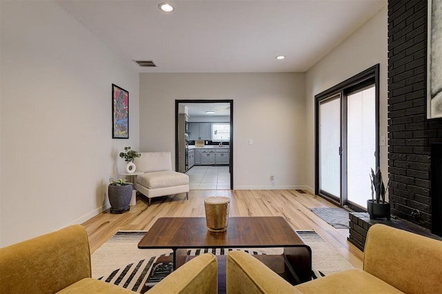 living room with light hardwood / wood-style flooring and a brick fireplace