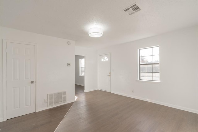 spare room featuring a textured ceiling and dark hardwood / wood-style floors