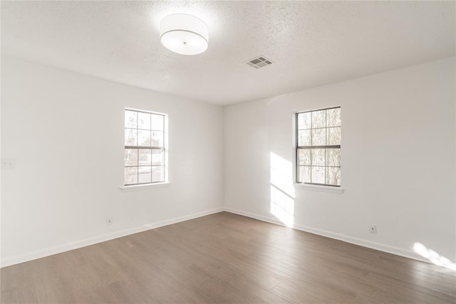 unfurnished room featuring a textured ceiling, dark hardwood / wood-style flooring, and plenty of natural light