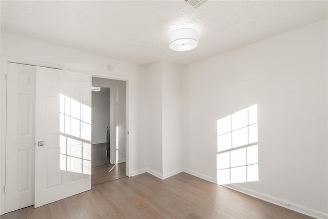 empty room with wood-type flooring and a textured ceiling