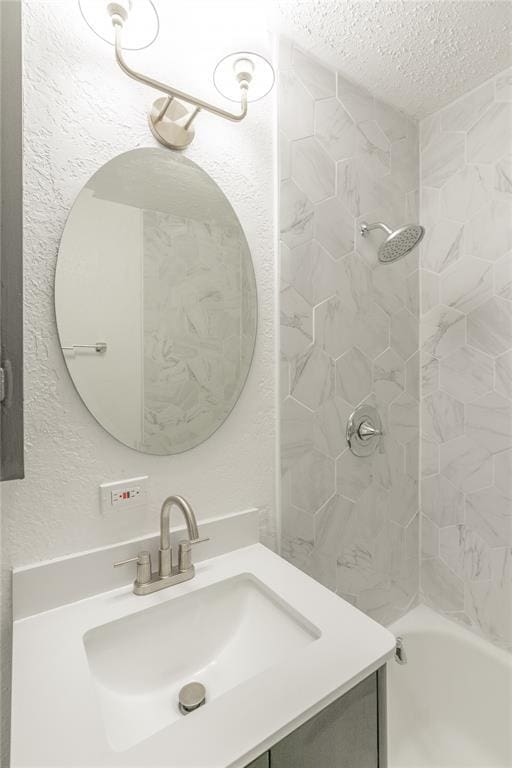 bathroom with vanity, a textured ceiling, and tiled shower / bath