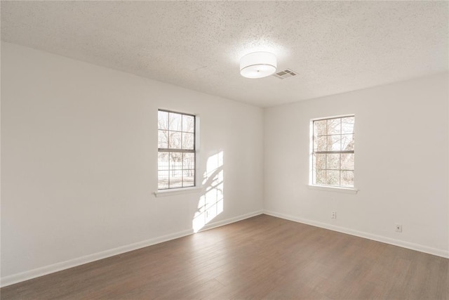 empty room featuring a textured ceiling and dark hardwood / wood-style floors