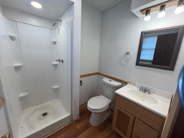 bathroom with walk in shower, toilet, vanity, and hardwood / wood-style flooring