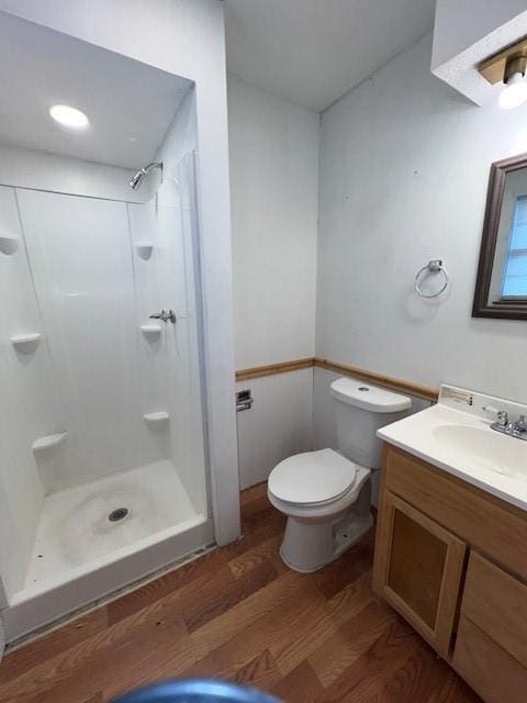 bathroom with wood-type flooring, vanity, toilet, and walk in shower