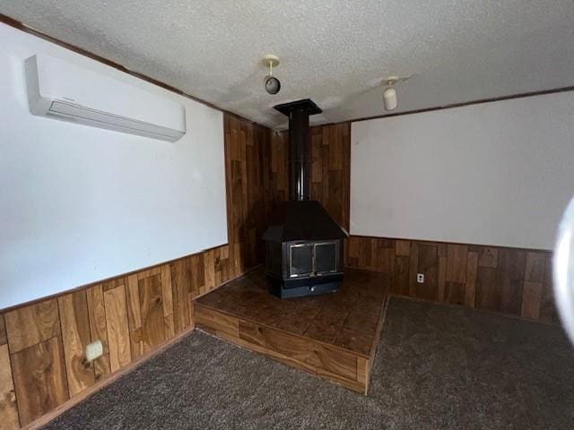 carpeted cinema room with an AC wall unit, a wood stove, and a textured ceiling