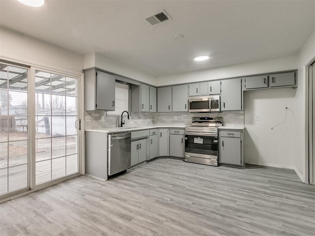 kitchen featuring gray cabinets, sink, light hardwood / wood-style flooring, and appliances with stainless steel finishes