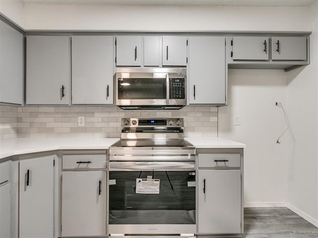 kitchen featuring decorative backsplash, appliances with stainless steel finishes, hardwood / wood-style flooring, and gray cabinetry