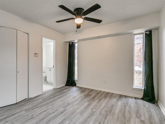 unfurnished bedroom featuring ceiling fan, light hardwood / wood-style floors, ensuite bathroom, and a closet