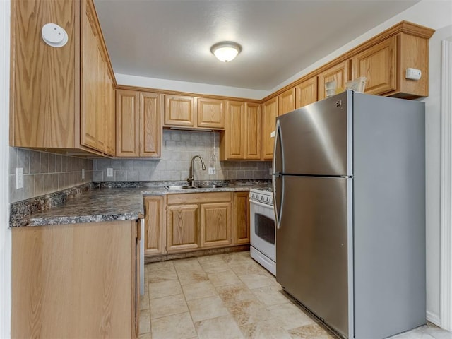 kitchen featuring stainless steel fridge, tasteful backsplash, gas range gas stove, and sink