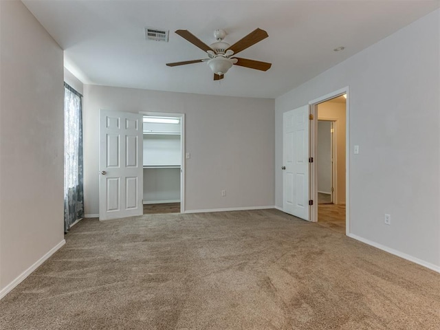 unfurnished bedroom featuring ceiling fan, light colored carpet, a spacious closet, and a closet