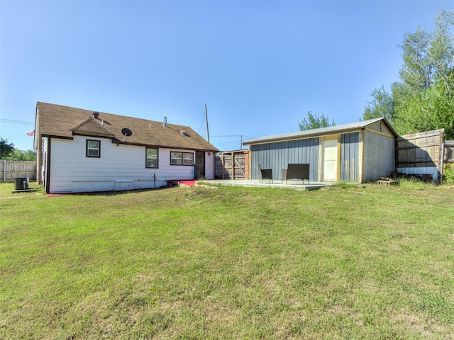 back of house with central air condition unit, a yard, and an outdoor structure