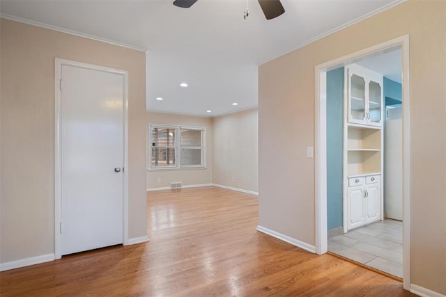 empty room featuring ceiling fan, ornamental molding, and light hardwood / wood-style flooring