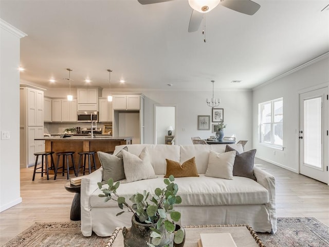 living area with ornamental molding, visible vents, light wood-style floors, and baseboards