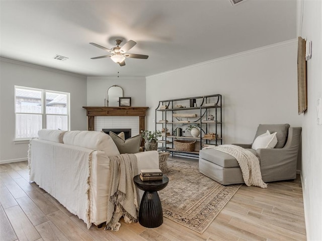 living area featuring light wood-style flooring, a fireplace, visible vents, and ornamental molding