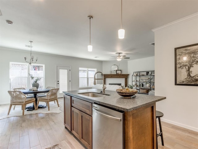 kitchen with brown cabinets, a fireplace, stainless steel dishwasher, a sink, and light wood-type flooring