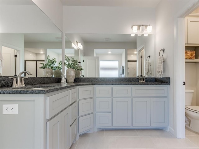 full bath featuring double vanity, toilet, a stall shower, a sink, and tile patterned floors