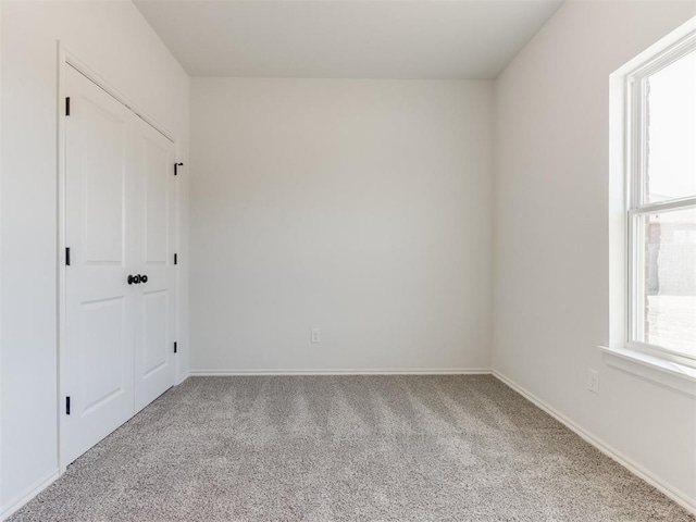 carpeted spare room featuring plenty of natural light and baseboards