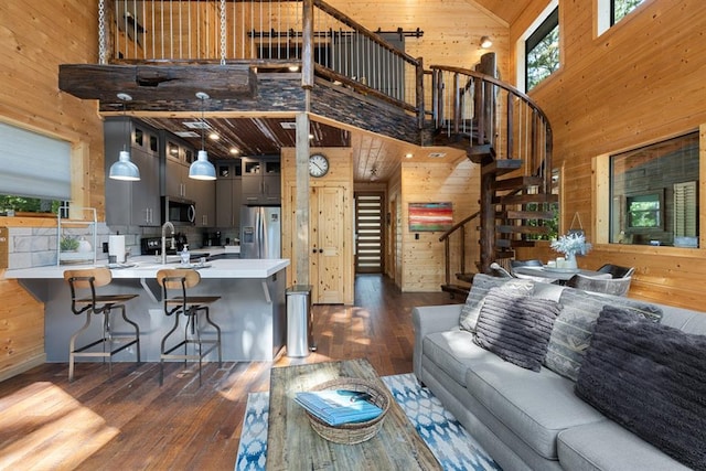 living room with dark hardwood / wood-style floors, high vaulted ceiling, wooden walls, and sink