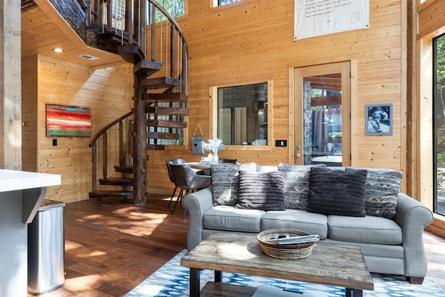 living room featuring wooden walls, plenty of natural light, and a towering ceiling