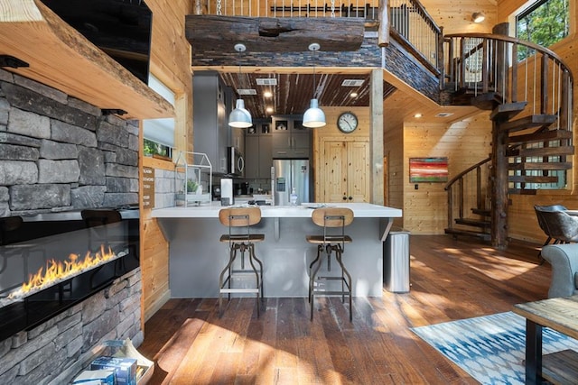 kitchen featuring a breakfast bar, a towering ceiling, kitchen peninsula, and wood walls